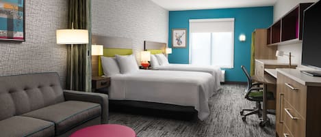 A hotel room with two beds, a sofa, a desk, and a TV.