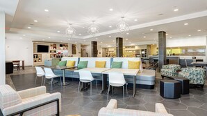 Eine geräumige Lobby mit einer modernen Sitzgruppe, einem Empfangsbereich und einem sichtbaren Küchenbereich im Hintergrund.