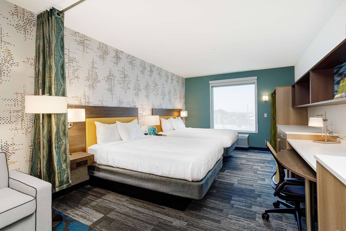 Une chambre d  ’hôtel avec deux lits, un bureau et une vue sur la ville.