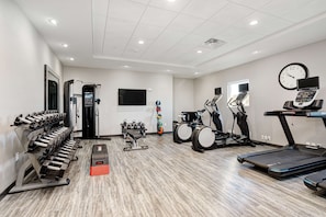 Une salle de sport équipée de tapis de course, de vélos elliptiques et de matériel de musculation.