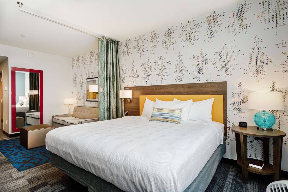Une chambre d’hôtel avec un grand lit, une table de chevet, une chaise, un bureau et un globe terrestre posé sur le bureau.