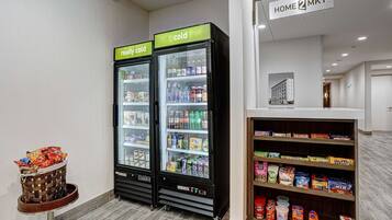 Two refrigerated beverage dispensers labeled "really cold" and "cold," with a snack bin and a shelf stocked with various food items.