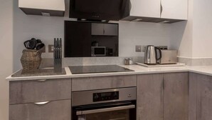 Een moderne keuken met een inbouwfornuis, magnetron en oven.