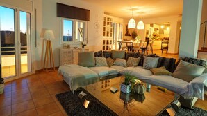 Uma sala de estar moderna com sofá, mesa de centro e área de jantar com cadeiras.