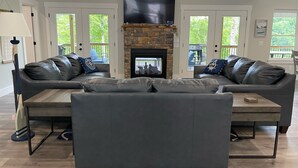 A spacious living room with a stone fireplace, two leather sofas, and a coffee table.