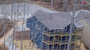 A multi-story house with a unique angular design, surrounded by a wooded area.