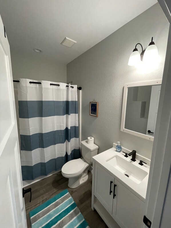 Baño con inodoro, lavamanos y cortina de ducha.