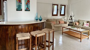 Un salon moderne avec un bar en bois, deux canapés, une table basse et un tableau au mur.