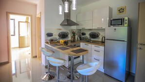 Een moderne keuken met een centraal eiland, roestvrijstalen apparatuur en hangende lampen.