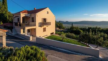 A two-story house with a balcony, a paved driveway, and a view of the countryside.