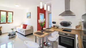 Een moderne keuken met een centraal eiland, roestvrijstalen apparatuur en een eethoek met barkrukken.