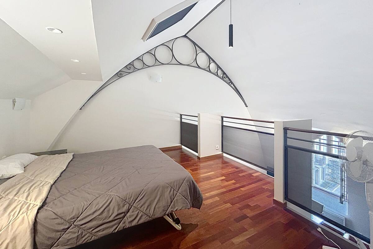 Un dormitorio con cama, ventana y balcón con barandilla.