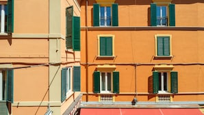 A multi-story building with green shutters on windows, a red awning, and a visible sign that reads "RESTAURANT". - Casa del sole by Studio Vita (Bologna)