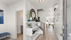 A modern hallway with a white console table, potted plants, and a decorative mirror. - Family Reunion Fun (#13 and #15) SLEEPS 32! GREAT AMENITIES! (St. George)