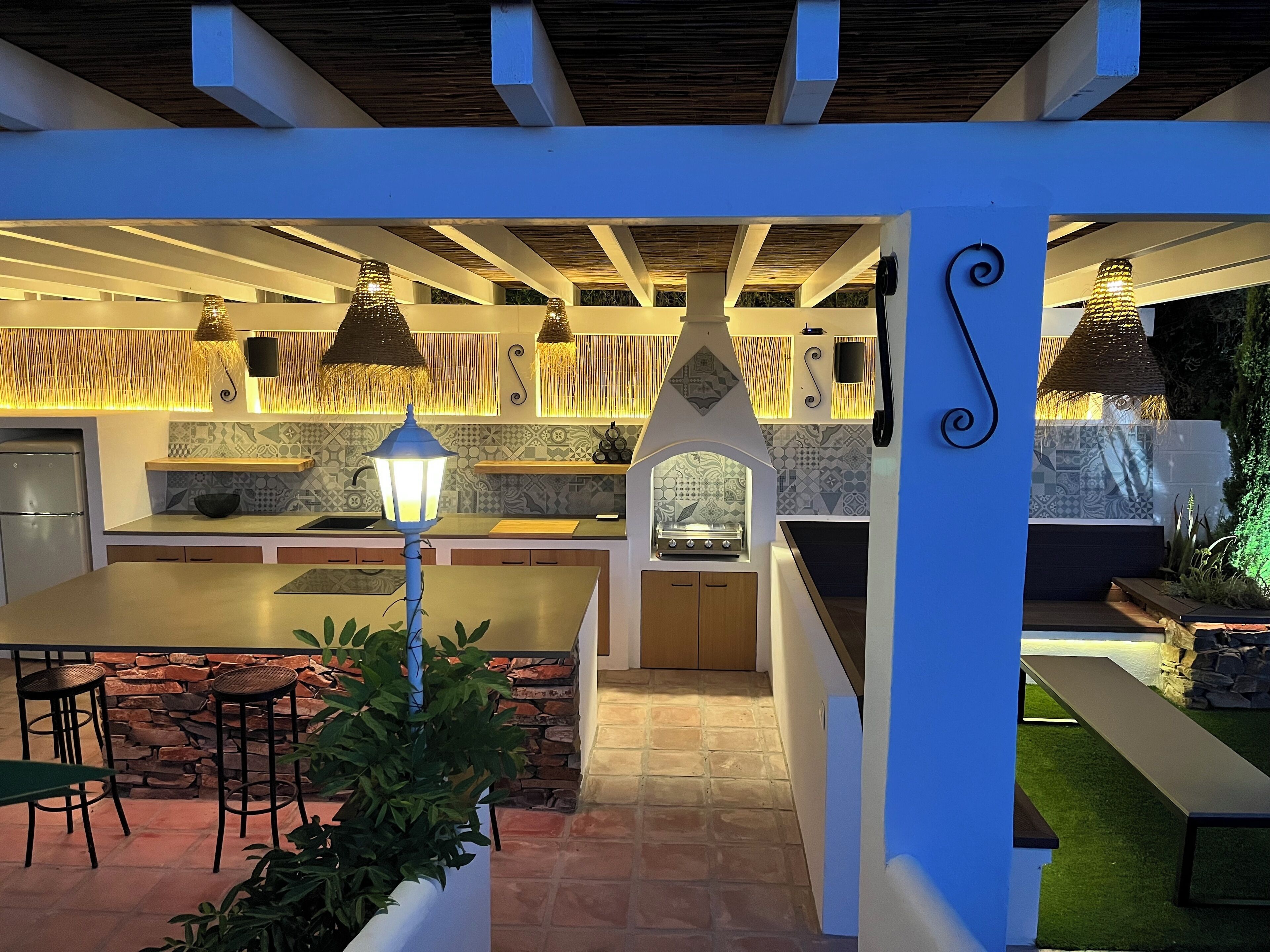 A modern kitchen with a central island, pendant lighting, and a stone wall backsplash.