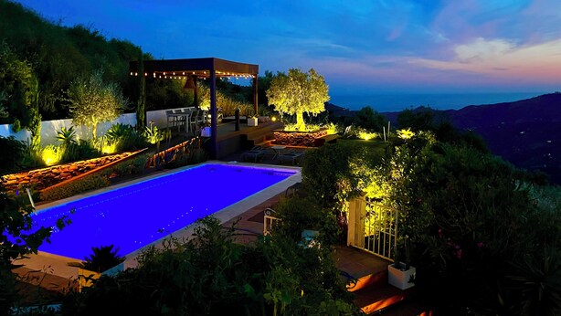 Ein Poolbereich mit Pergola, Sitzgelegenheiten und Blick auf die Landschaft.