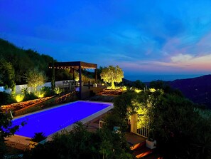 Zona de piscina con pérgola, asientos y vistas del paisaje.