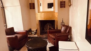 Un salon avec une cheminée, des canapés en cuir, une table basse et un miroir.