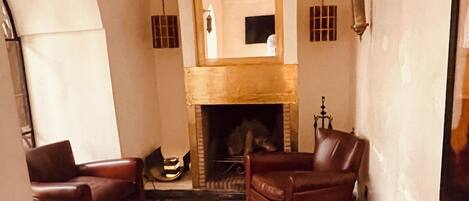 A living room with a fireplace, leather sofas, a coffee table, and a mirror.