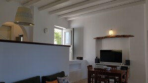 A modern living room with a sofa, TV, and dining area. - Amorgos the olive garden above the sea I (Katapola)