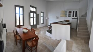 A modern kitchen with a dining area, a staircase, and a view of the outside. - Amorgos the olive garden above the sea I (Katapola)