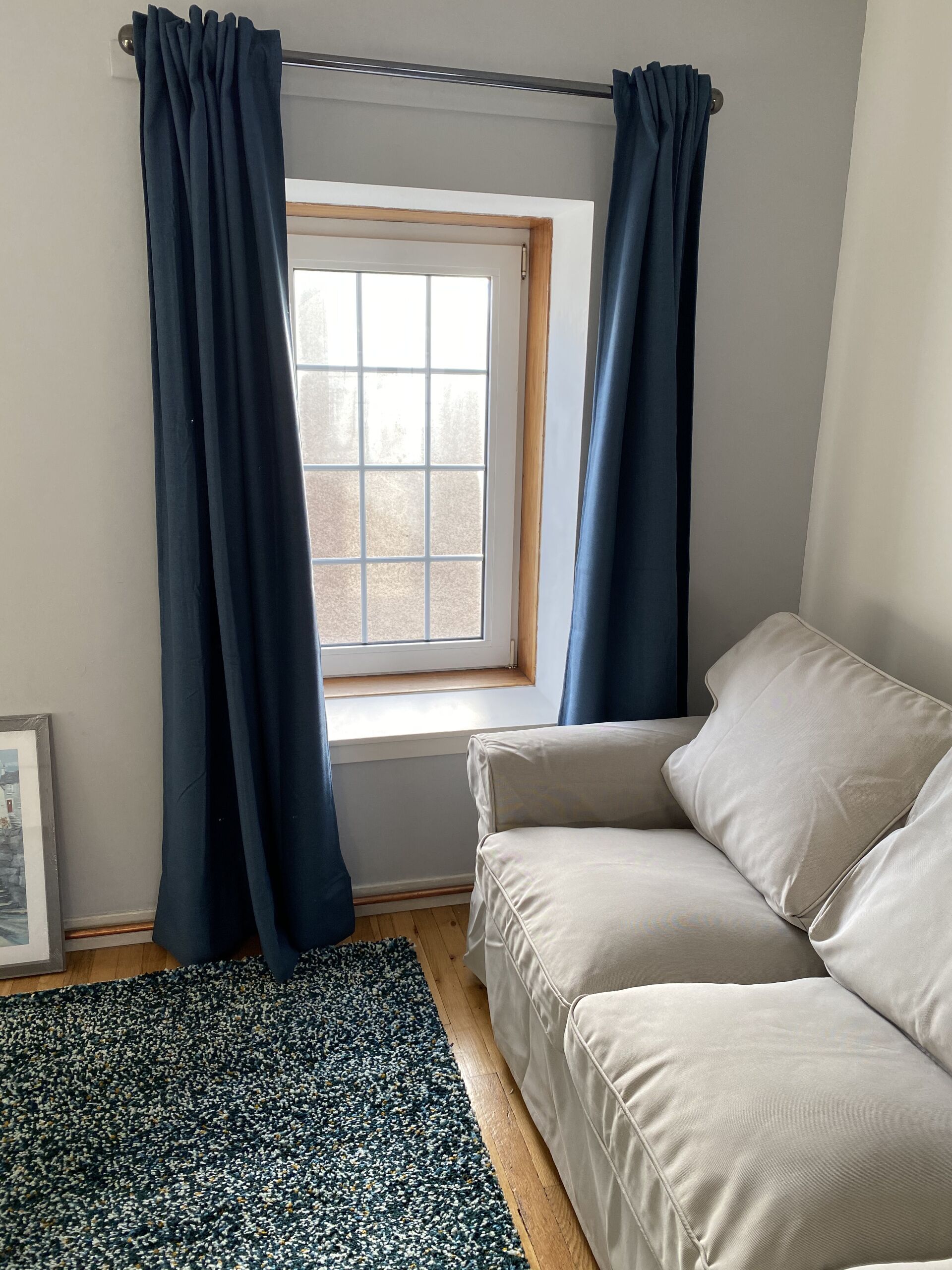 Ein Zimmer mit Fenster, einer Couch und einem gemusterten Teppich.