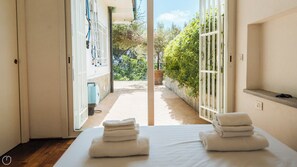 A hotel room with a bed, a bathroom, and a view of a garden.