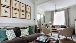 A living room with a brown sofa, two armchairs, a coffee table with books, and framed bird pictures on the wall. - First Street III by Onefinestay (London)