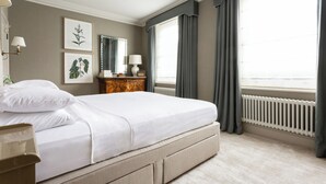 A hotel room with a large bed, a dresser, a mirror, and two windows with curtains. - First Street III by Onefinestay (London)