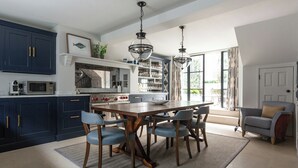 A spacious kitchen with dark blue cabinets, a central island with chairs, and pendant lighting. - First Street III by Onefinestay (London)