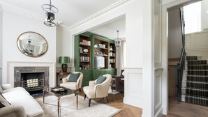 A living room with a fireplace, a green bookshelf, and a staircase. - First Street III by Onefinestay (London)