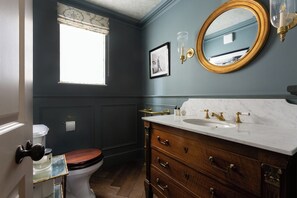 A bathroom with a toilet, vanity with a marble countertop, a mirror, and a window. - First Street III by Onefinestay (London)