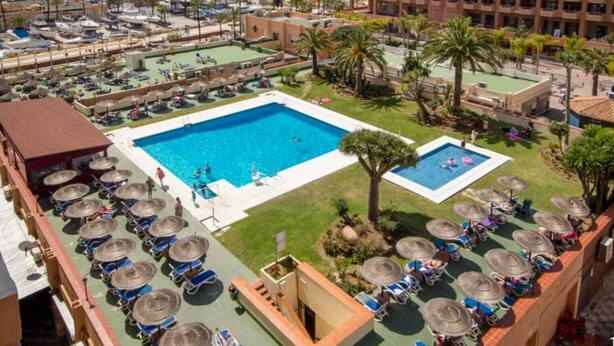 Un hôtel doté de plusieurs piscines, de chaises longues et de parasols.