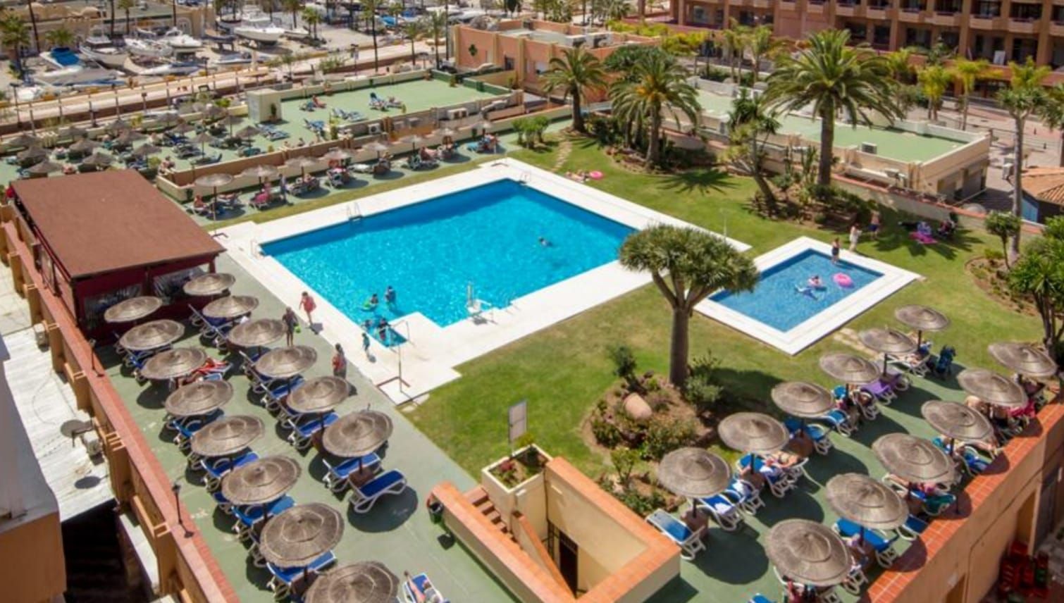 A hotel with multiple swimming pools, sun loungers, and umbrellas.