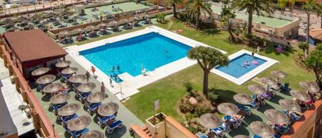 A hotel with multiple swimming pools, sun loungers, and umbrellas.