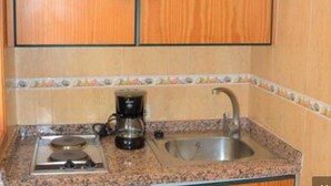 Une cuisine équipée d’une cuisinière à gaz, d’une machine à café et d’un évier.