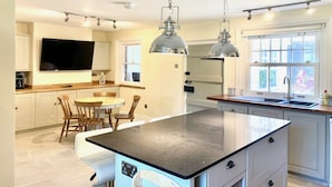 A modern kitchen with a central island, pendant lighting, and a large window providing natural light.