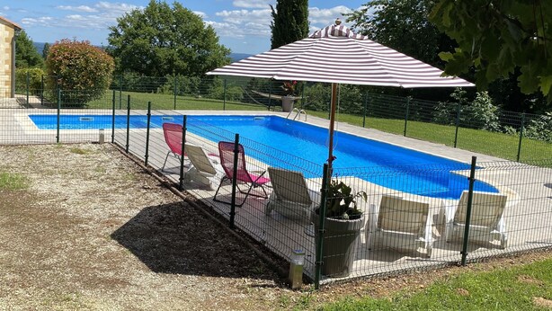 A backyard with a swimming pool, surrounded by a fence, and a large umbrella providing shade. - Vacation home with private pool 5min from Sarlat (Marcillac-Saint-Quentin)