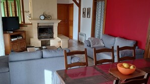 A living room with a sofa, a dining table with chairs, a fireplace, and a television. - Vacation home with private pool 5min from Sarlat (Marcillac-Saint-Quentin)