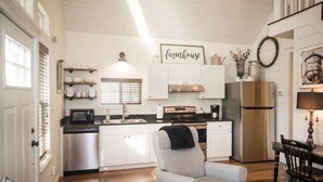 Une cuisine avec des armoires blanches, un réfrigérateur en acier inoxydable et un panneau décoratif de style rustique.