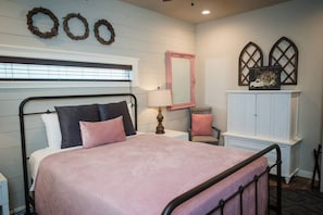 A bedroom with a bed, a nightstand, a lamp, a chair, a mirror, and a cabinet. - The Gruene Haus at Gruene B&B (New Braunfels)