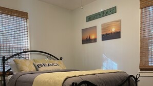 Un dormitorio con una cama, un ventilador de techo y un letrero que dice 'BEACH HOUSE'.