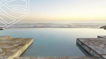 An infinity pool with a view of the ocean at sunset.