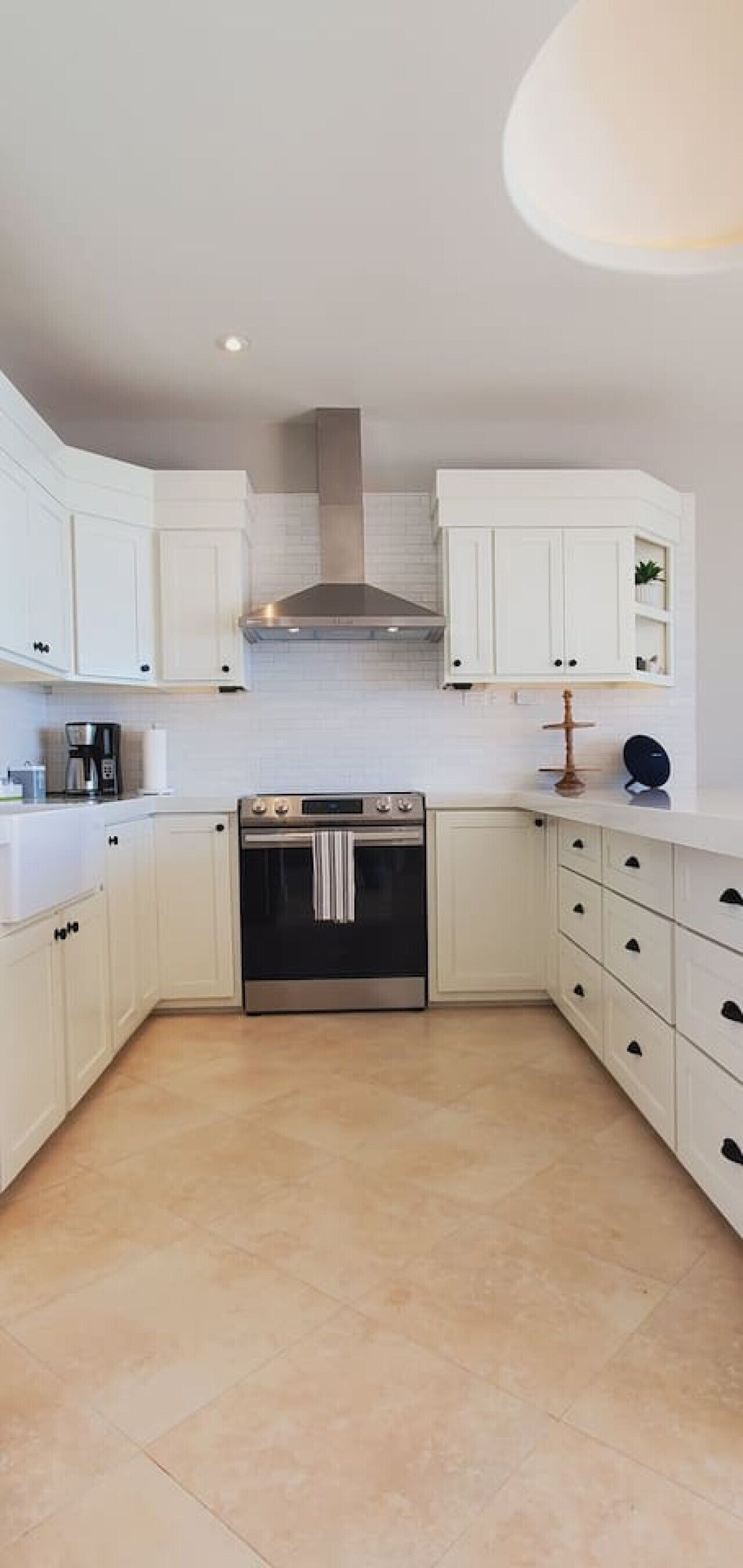 A modern kitchen with white cabinetry, a stainless steel range hood, and a built-in oven.