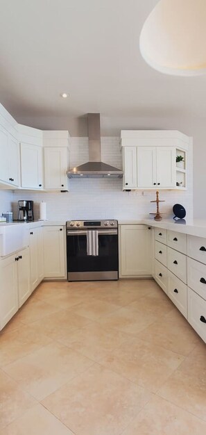 A modern kitchen with white cabinetry, a stainless steel range hood, and a built-in oven. - BEACH FRONT CONDO, PRIVATE BEACH & AMAZING VIEWS!! (Rosarito)