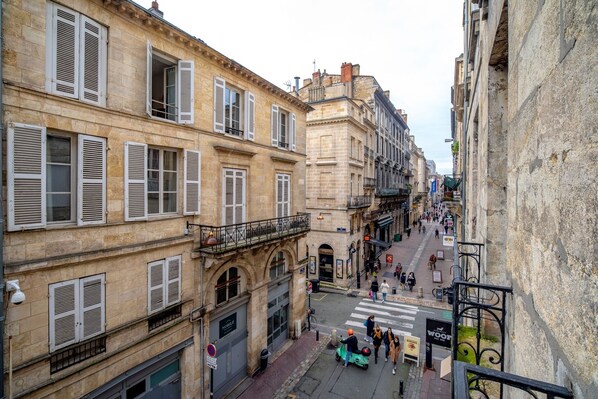 A narrow street with historic buildings, a pedestrian crossing, and a scooter parked on the sidewalk.
