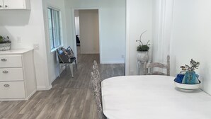 A spacious dining area with a large white table, wooden chairs, and a white cabinet. - The Bluebird House Near Wineries Historic Downtown Murrieta  (Murrieta)