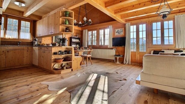 L’intérieur d’un chalet en bois rustique comprend une cuisine, un coin repas et un salon.