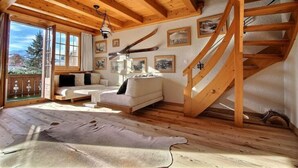 Un intérieur en bois avec un canapé, un escalier et des tableaux encadrés accrochés au mur.