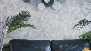 A black leather sofa with yellow cushions, a textured grey wall, and a decorative wall hanging. - La Lilla - Piscine - Wifi (Chauve)